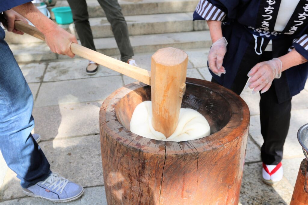 木製の杵と臼で餅つきする様子