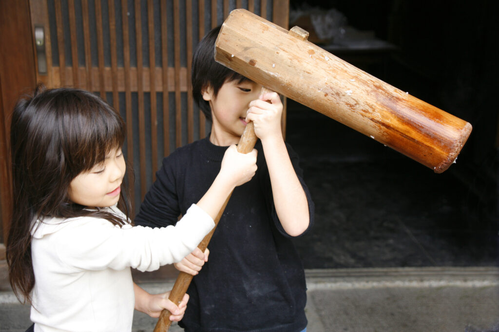 協力して杵を持つ兄妹