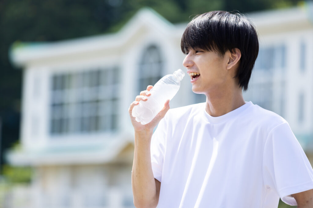 白いTシャツで水を飲む人